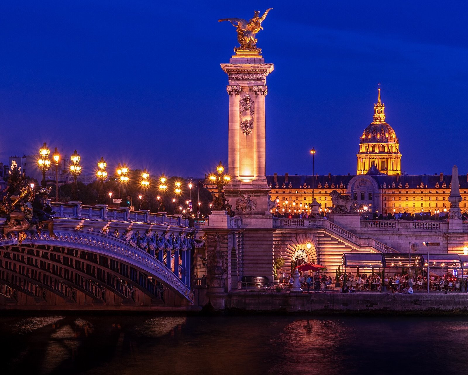 Le pont Alexandre III et les Invalides illuminés la nuit, vus depuis la Seine
