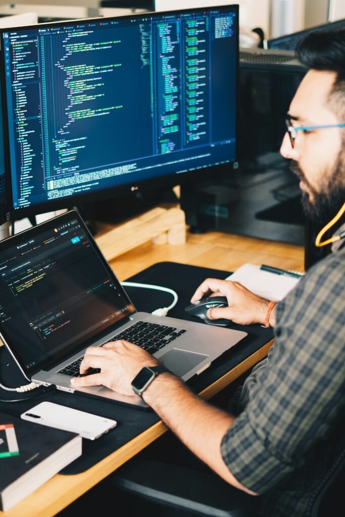 Software developer writing code on two screens